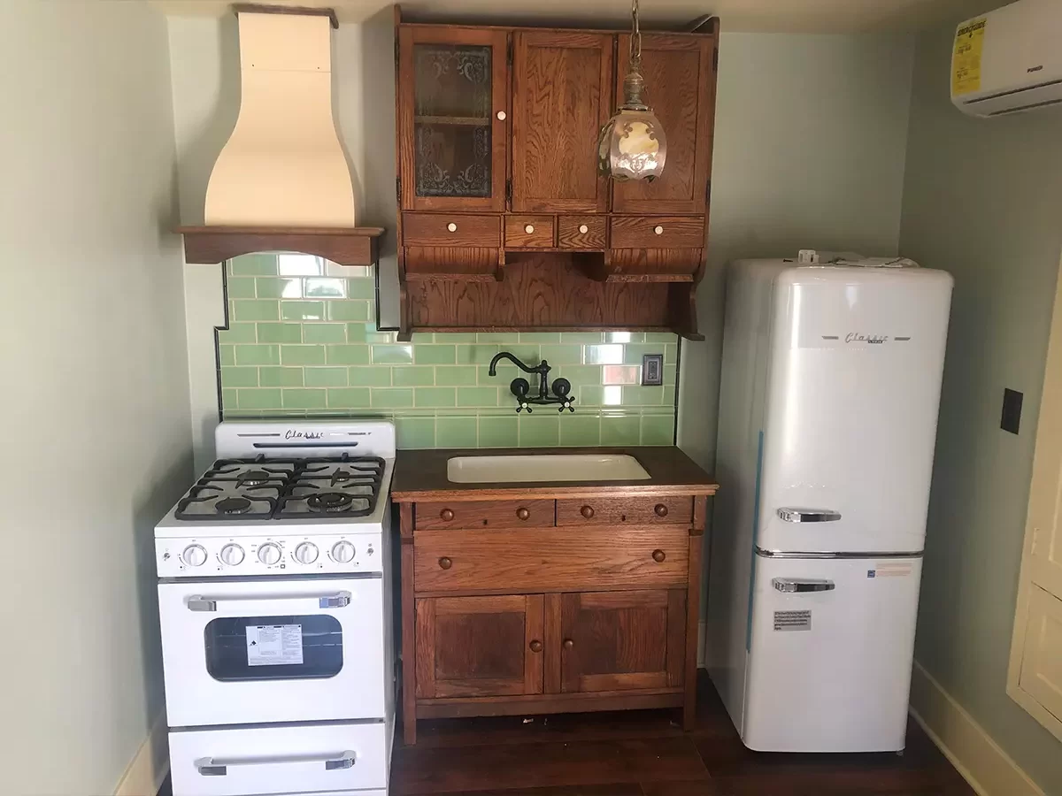 A dated kitchen with beautiful old cabinets and white kitchen appliances