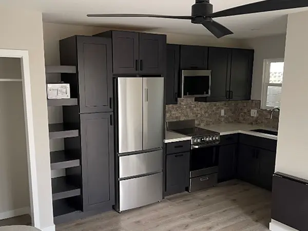 Black kitchen cabinets with dark pulls and engineered wood floor