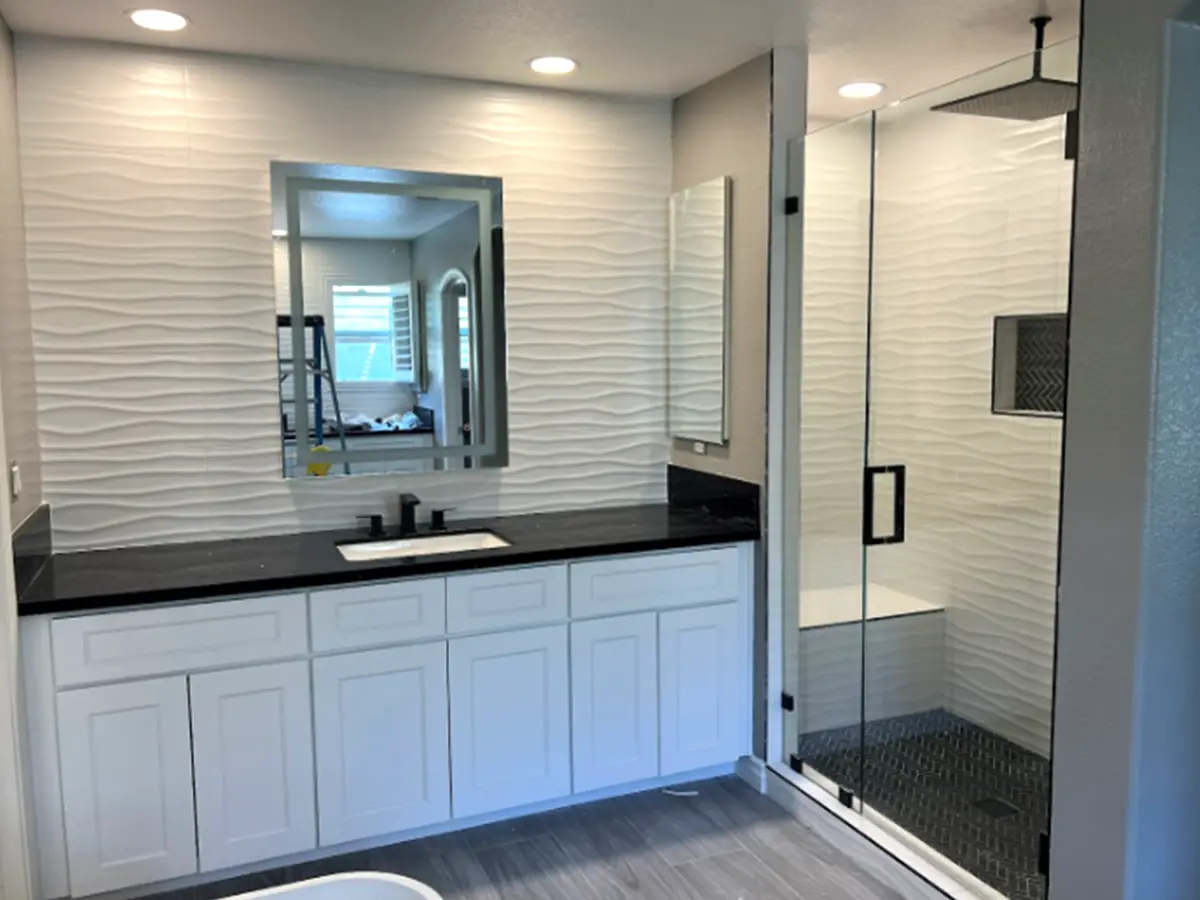 A dark countertop with cabinets and a glass walk-in shower