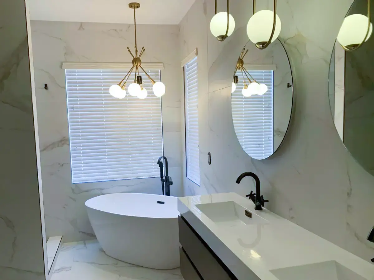 A bathroom with pendant lights, freestanding tub, and a double vanity with a white top
