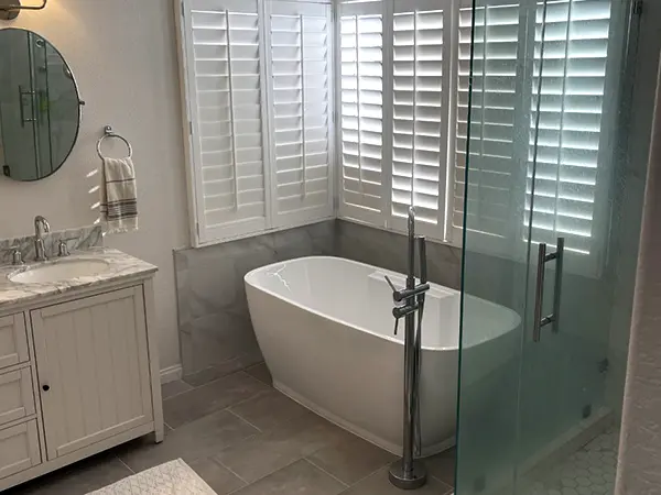 A bathroom with glass walk-in shower with freestanding tub