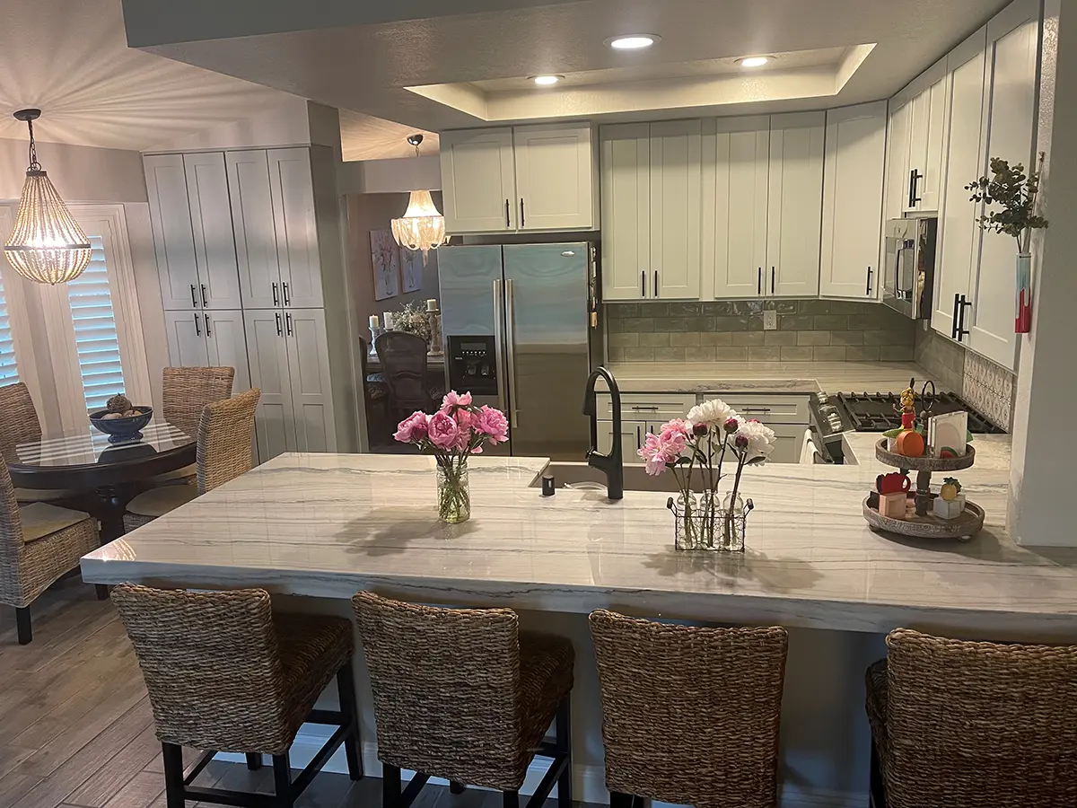 A quartz countertop with light gray kitchen cabinets with flowers