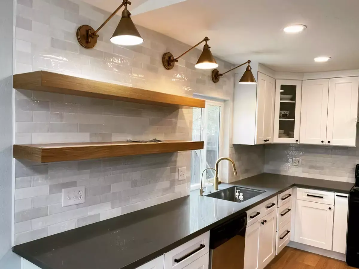 A tile backsplash in a kitchen with white kitchen cabinets with black handles