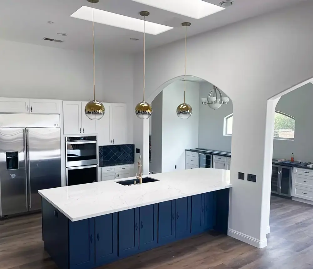 A beautiful quartz countertop on a large island and a beautiful dark blue tile backsplash with engineered wood floor